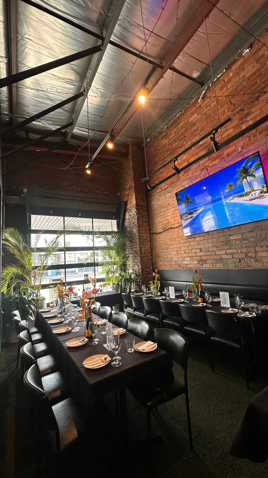 The Private Room set with long tables, fresh flowers and a big screen against the brick wall